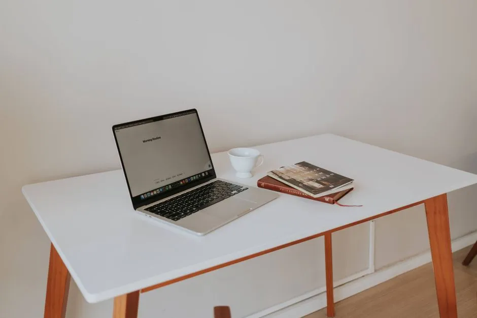 A modern home workspace with a laptop and a stack of books on the desk